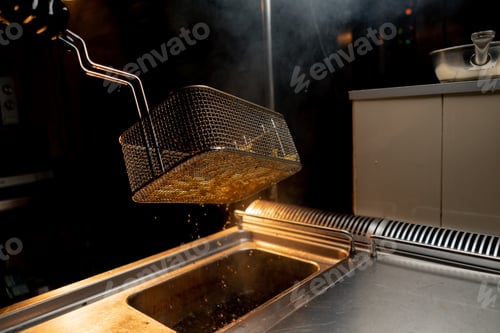 Preview: kitchen in the hotel restaurant the chef takes out delicious french fries from the fryer oil drips