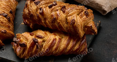 Preview: Three golden brown maple pecan braid pastries are arranged on a dark, textured surface.