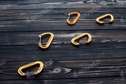 Preview: Isolated photo of climbing equipment. Parts of carabiners lying on the wooden table