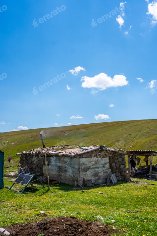 Preview: Rustic mountain hut with smoking chimney in green landscape