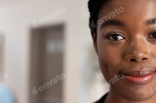 Preview: Half face portrait of smiling african american female doctor in hospital corridor with copy space