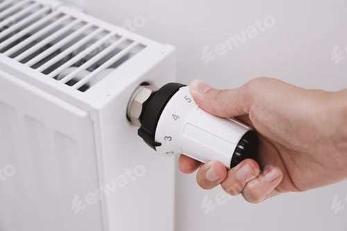 Preview: Woman hand adjusting temperature on heat radiator