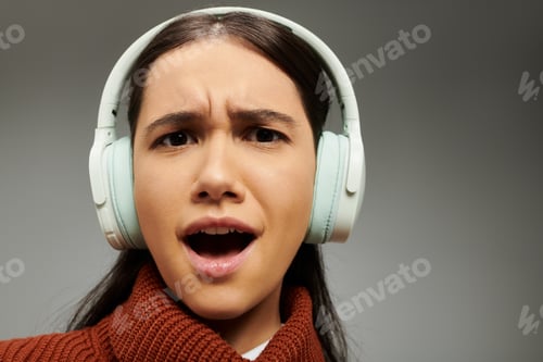 Preview: Emotional young woman in stylish attire listens intently to music with headphones on at home