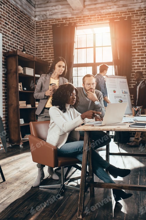Preview: multiethnic group of colleagues working together on new project in modern loft office with backlit