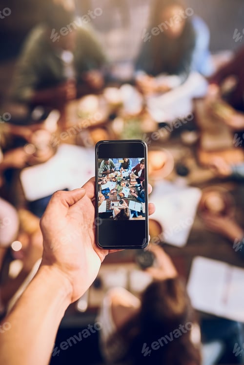 Preview: Cropped shot of a man taking a picture of colleagues having a business lunch