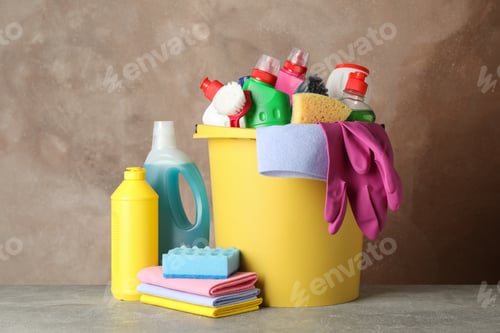 Preview: Bottles with detergent and cleaning supplies on brown background, space for text