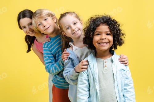 Vista previa: Sonriente, positivo y diverso grupo de niños multinacionales felices posando sobre fondo amarillo