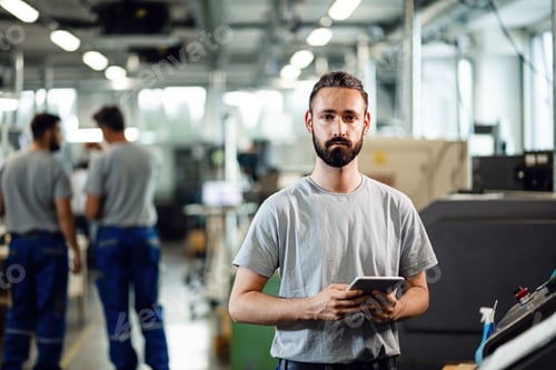 Preview: Portrait of young industrial engineer with a touchpad looking at camera.