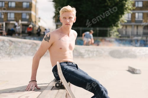 Preview: Young male skateboarder looking over his shoulder in skatepark