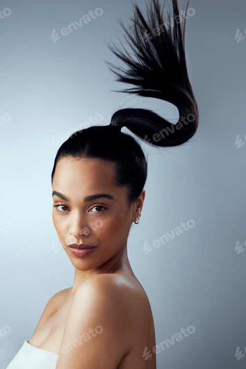 Preview: Studio shot of an attractive young woman holding her hair against a grey background