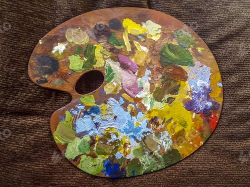 Preview: Top view of a painter's palette with lot's of colors placed on a brown surface