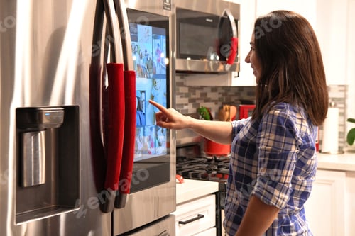 Preview: Modern technology. Young millennial woman using smart technology on a refrigerator