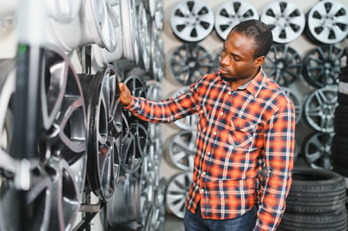 Preview: African american male customer choosing alloy wheel rims at car repair service or auto store