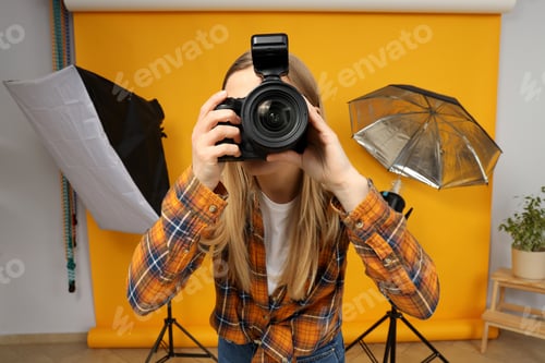 Preview: Beautiful girl photographer in the photo studio, on a yellow background.