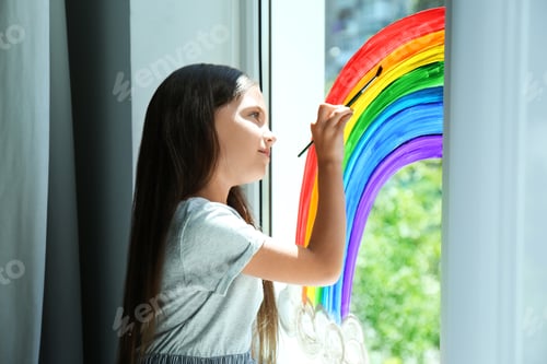 Preview: Little girl drawing rainbow on window indoors. Stay at home concept