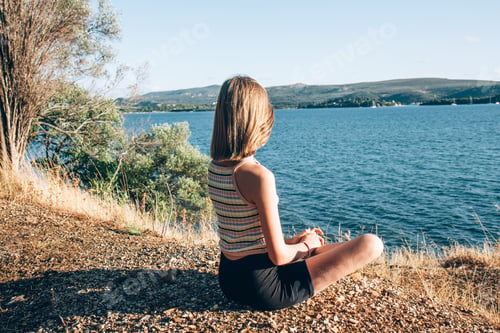Preview: Young beautiful teenage girl meditating on the seashore and enjoys the landscape
