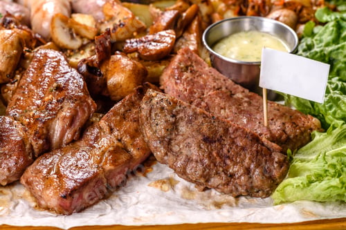 Preview: Several types of roasted meat with spices and herbs on a wooden tray