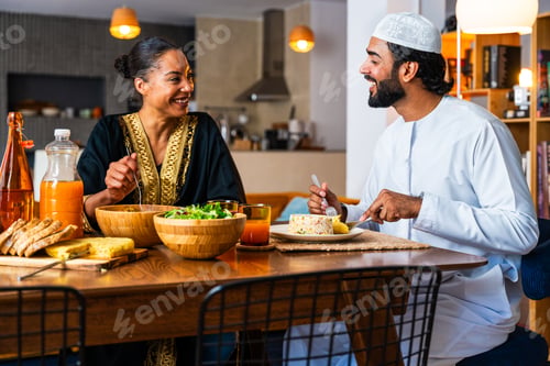 Preview: Happy beautiful young arab couple with emirati clothing having meal together at home