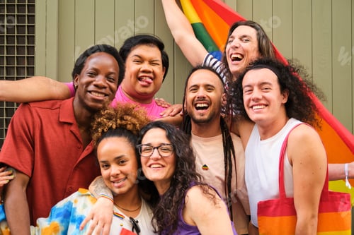 Preview: A group of people are posing for a picture with a rainbow flag at Pride Day.