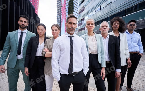 Preview: Multicultural business team headed by boss. Posing to camera outdoors building office.