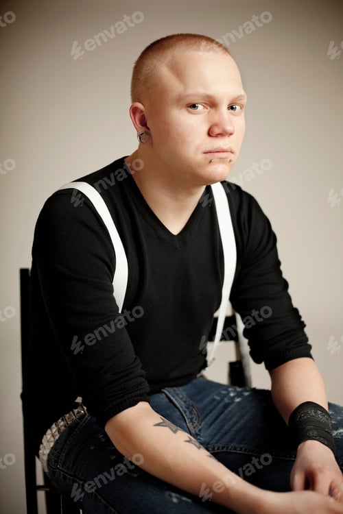 Preview: Portrait of young man sitting on chair against wall