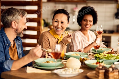 Preview: Happy Asian woman talking to her friends while having lunch in dining room.