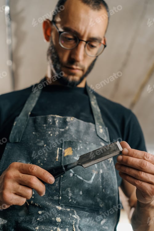 Preview: Male painter sculptor artisan works with spatula in art workshop