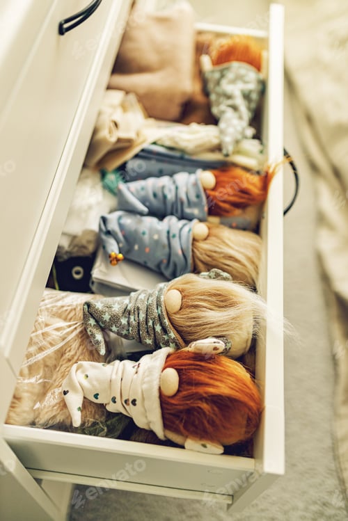 Preview: Bearded gnomes in caps lie in a chest of drawers. Handmade soft toy. Vertical shot. Soft focus