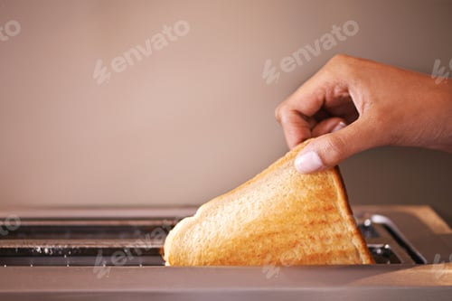 Preview: Golden brown and ready to munch. Cropped shot of a woman taking toast out of a toaster.