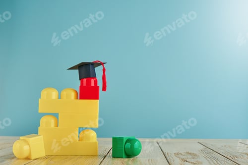 Preview: Multicolored construction cubes for children and black and masters cap or an oxford cap on blue