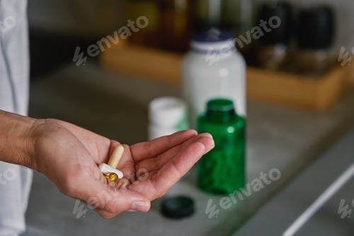 Preview: Woman holding pills in hand. Person taking supplements