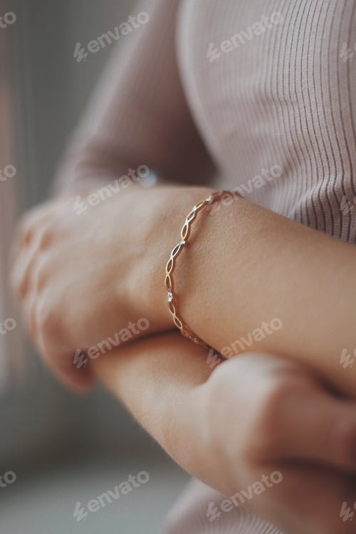 Preview: Vertical closeup shot of a female wearing a golden bracelet