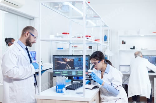 Preview: Male scientist taking notes on tablet pc during virus study
