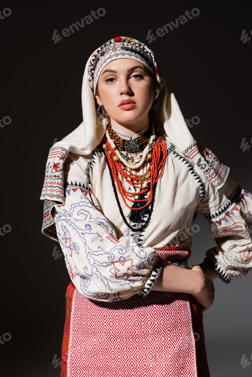 Preview: young ukrainian woman in traditional shirt with ornament and red beads posing with hand on hip on