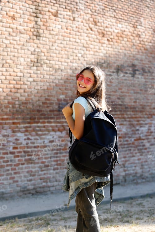 Preview: teenager with backpack and fashionable sunglasses on the playground