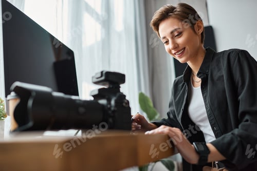 Preview: cheerful good looking woman working with drawing tablet and her camera in front of computer
