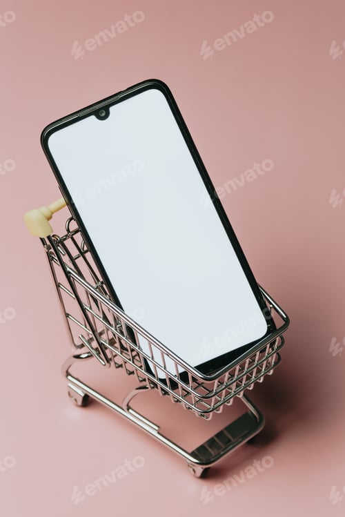 Preview: Shopping cart with a blank mobile phone over a pastel pink background, e commerce