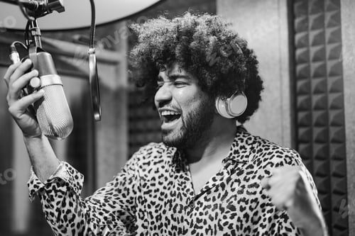 Preview: Male singer using microphone and headphone recording audio inside music studio