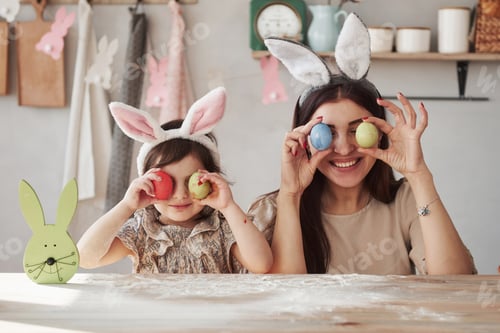 Preview: Mother and daughter in bunny ears at easter time have some fun in the kitchen at daytime
