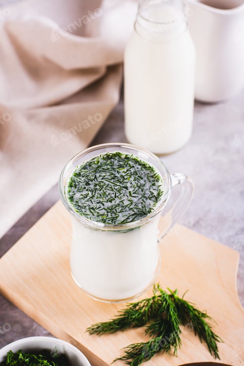 Preview: Glass with fresh Turkish ayran with dill and greens on the table vertical view