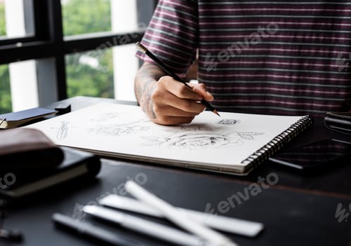 Preview: Closeup of tattooed hand with drawing artwork