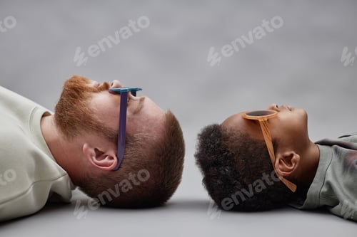 Preview: Profile of Man in Sunglasses Lying Head to Head with Black Boy in Studio
