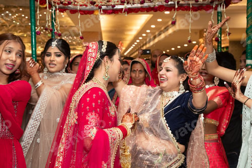 Preview: Women in traditional Indian attire and henna designs dancing under a floral canopy at a wedding