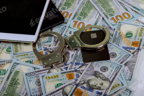 Preview: Handcuffs on a of US dollar banknotes credit card and using laptop