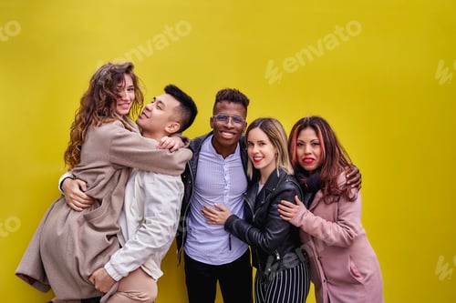 Preview: Multiracial young people having fun on yellow background. Group of friends of various ethnicities.