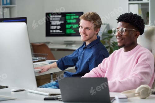 Preview: Young Man and Young Black Man Collaborating in Office Workspace
