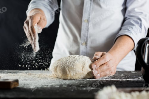Preview: Cook sprinkles dough with flour on the kitchen table