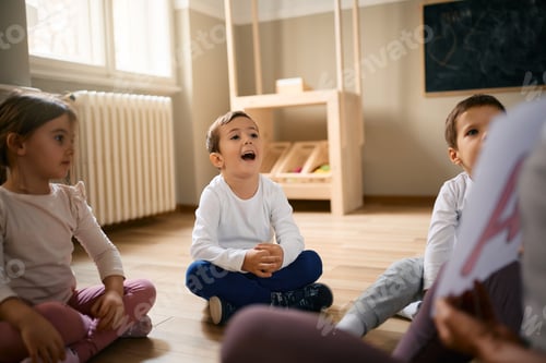 Preview: Happy little boy and his friends learning alphabet with their teacher at preschool.