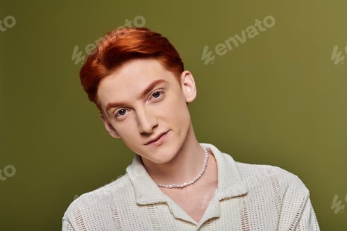 Preview: Emotional young man with striking red hair exuding charm and personality against a green backdrop