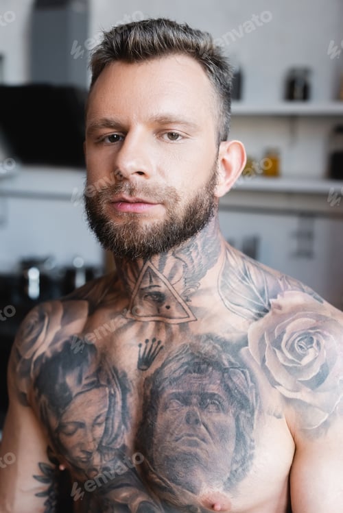 Preview: confident, muscular man looking at camera while standing in kitchen